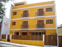 Kira's Boutique Hotel- Gold-orange Außenfassade mit Holzfenster