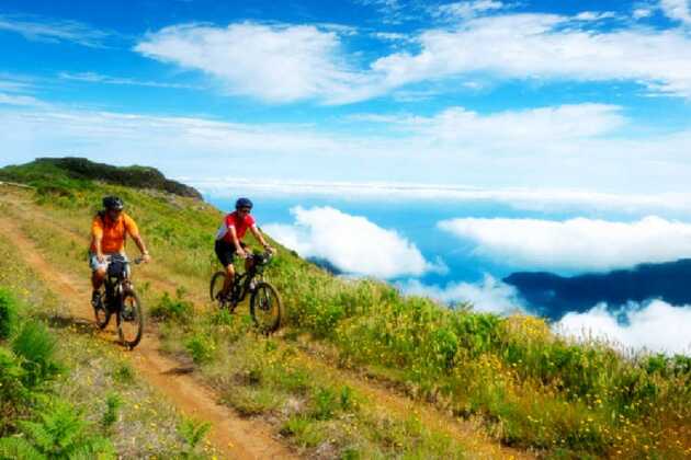 zwei Radfahrer fahren Rad hoch über den Wolken auf Madeira