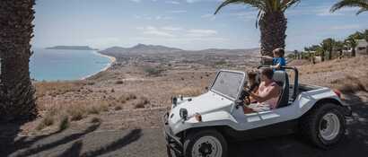 Familie sitzt im Buggy und schaut auf das Meer und die Küstenlinie Porto Santos mit ihren goldgelben Sandstränden.