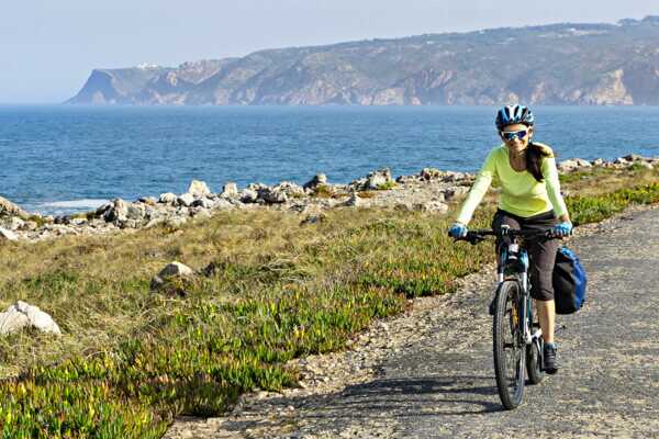 Bikerin an der Silberküste an der Atlantikküste Portugal. Im Hintergrund Meer und Felsküste.