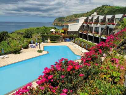 Caloura Hotel Resort - Poolanlage mit Liegen und Sonnenschirmen - Meerblick inklusive