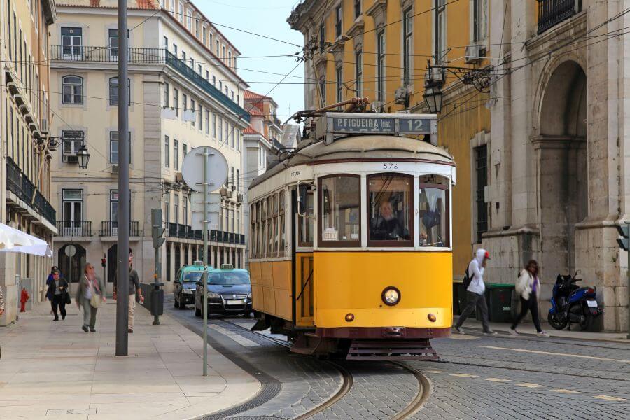 Eine gelbe Strassenbahn schiebt sich durch die Strassen der portugiesischen Hauptstadt Lissabon